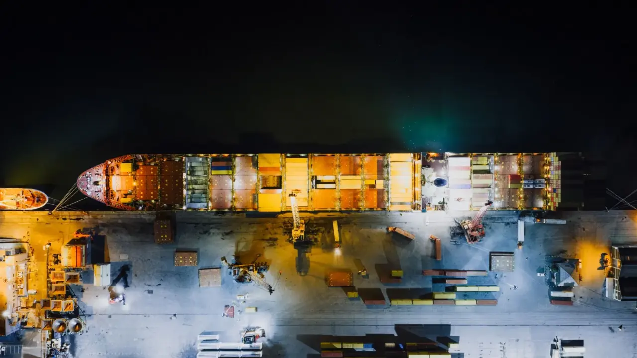 An aerial view of a container ship loading at a lit terminal at night