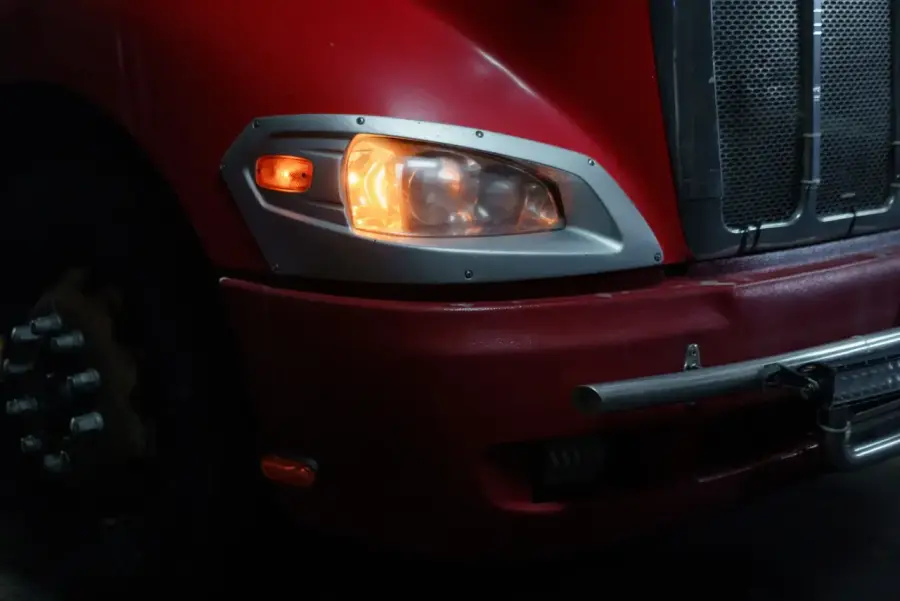 A freight truck at night, headlights on
