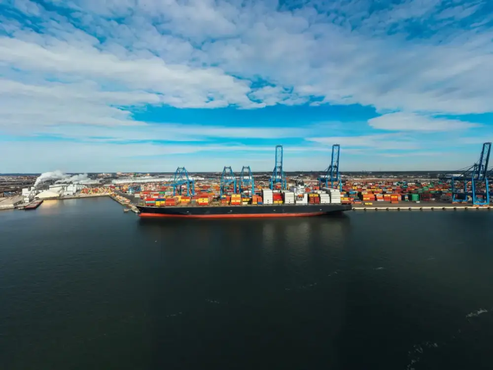 A cargo ship moored in a modern industrial port, seen from above